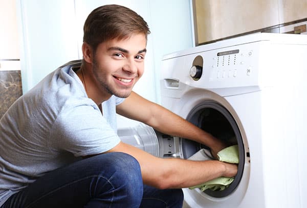 Un uomo estrae il bucato da una lavatrice