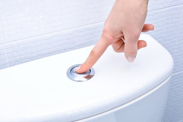 Presionando un botón en la taza del inodoro